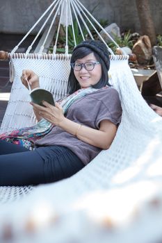 portrait of beautiful asian woman relaxing time reading book on cradle happiness emoton with smiling face