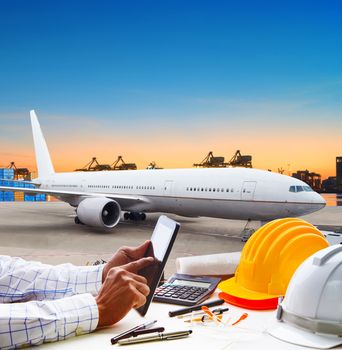 hand touching on computer tablet on working table against air plane parking in airport runway use for freight,cargo logistic and air transportation theme