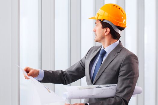 Architector in hardhat and business suit with construction plans