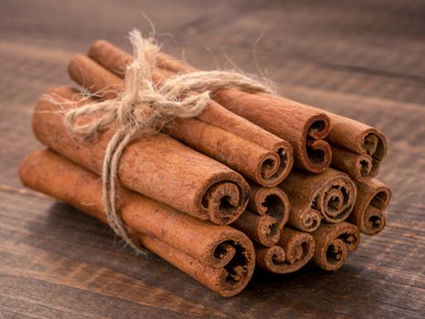 Ground cinnamon, cinnamon sticks, tied with jute rope on wooden background. Close up