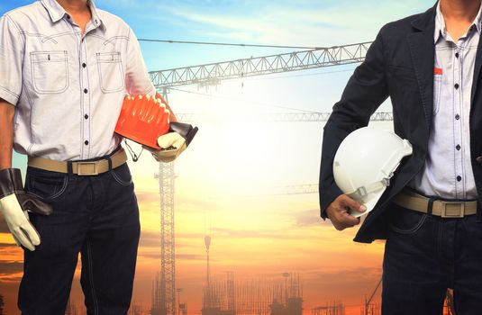 two engineer man working with white safety helmet against crane and  building construction site use for civil engineering and construction industrial business