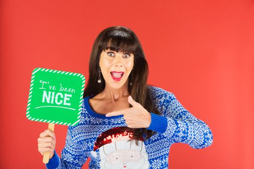 Happy single woman in ugly knitted sweater pointing to nice sign over red background