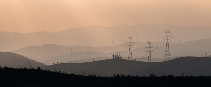 Silhouettes of electric towers in the foggy morning.