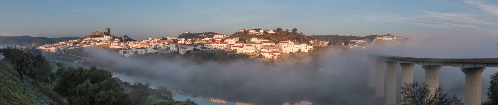 Wide view of Mertola village engulfed on a foggy morning.