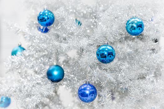 Blue baubles hanging on silver artificial christmas tree, good as background