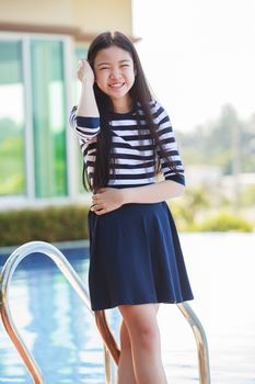 portrait of asian teen age smiling face standing in home swiming pool with relax and happy emotion