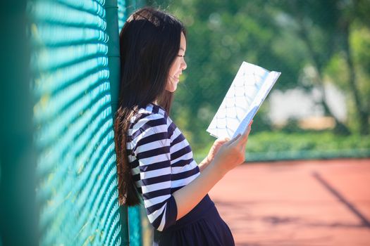 asian girl and school book in hand toothy smiling face with happiness emotion in green park use for education theme and related