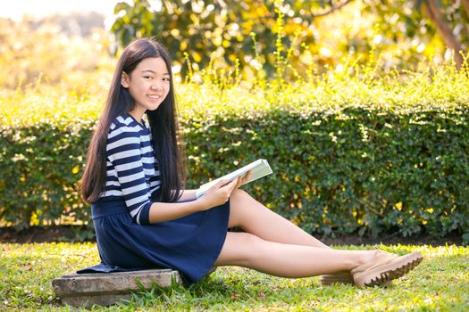  portrait of asian teen twelve years old and school book in hand with toothy smiling face