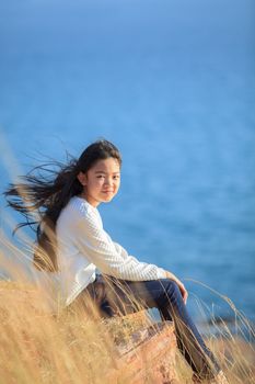 portrait of asian girl relaxing emotion sitting in grass field and windy evening use for teen age leisure and activities traveling vacation time