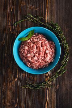 Minced meat with herbs on wooden background