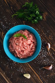 Minced meat with herbs on wooden background