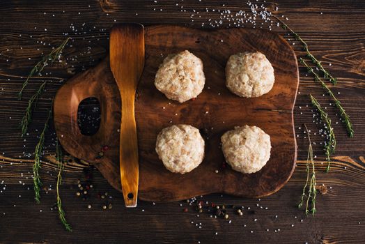 Above view of uncooked meatballs in a dark rustic wooden setting