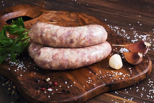 Raw sausages with garlic and parsley on the cutting board