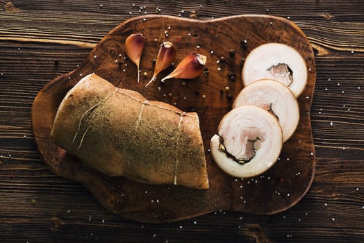 Lard roll with salt and garlic, wooden background