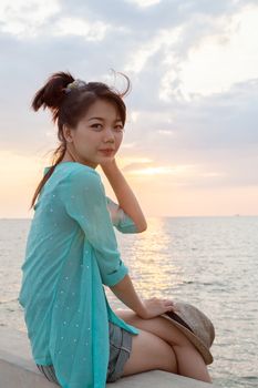 portrait of asian woman relaxing vacation holiday at sea side with sun set sky background