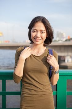 head shot smiling face of asian woman with backpack standing outdoor