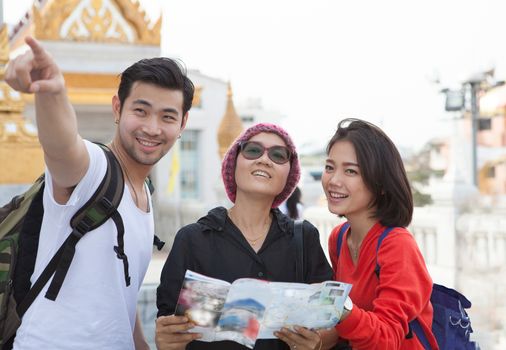traveling man woman and senior tourist holding travel guide book in hand pointing to destination for visiting 