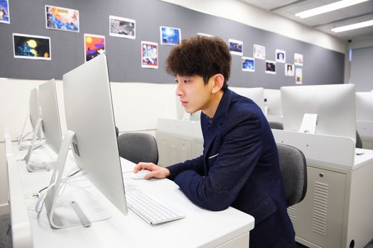 young asian man using computer in classroom