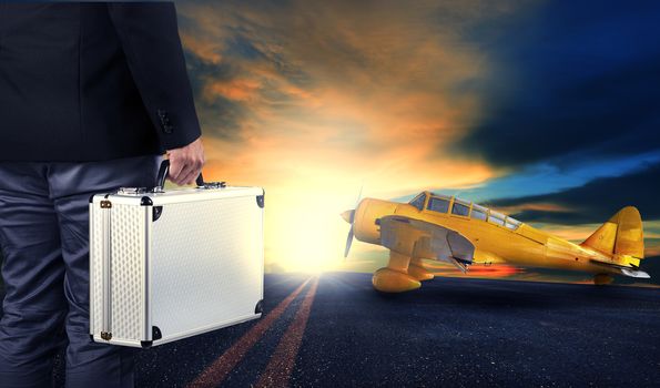 business man with metal strong luggage standing in airport runways with yellow old yellow propeller plane use for air transport and people traveling theme,concept,conception,conceptual,