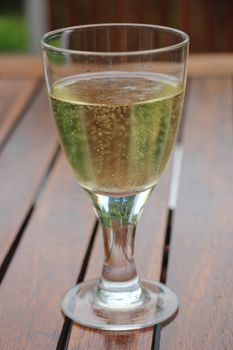 Glass of sparkling white wine on a wooden table