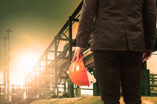 engineering man and safety helmet standing against beautiful light sun shine in heavey petrochemical industry estate 