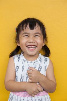 close up face of asian ked toothy smiling facial face with happiness emotion on yellow wall use for children lovely emotion and dental health theme