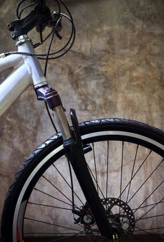 close up front wheel tire of mountain bike against grungy cement wall use for bicycle and biking conceptual