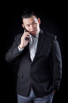 portrait of asian business man talking mobile phone against blac background photography by low key light technique in studio