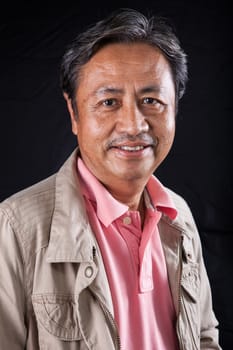 portrait close up smiling happiness face of 59s years old asian man with studio light against black backgrund