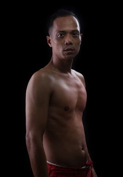 portrait face of young asian man show muscle on arm and chest with studio lighting against black background