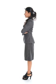Full length side view of Indian businesswoman standing arms crossed isolated on white background. 