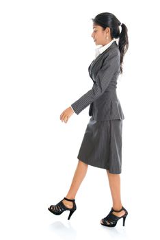 Full length side view of Indian businesswoman walking isolated on white background. 