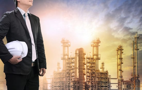 engineering man with safety helmet standing against oil refinery plant in heavy petrochemical industry estate use for fossil energy and petroleum power topic