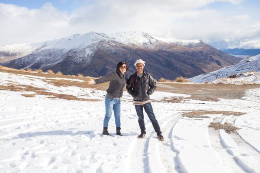 couples of  asian traveler take a photograph with happiness face on white snow on mountain ground in queen town south island new zealand