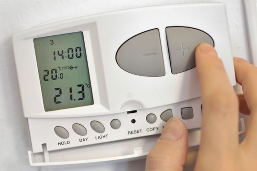 hand pressing button on digital thermostat