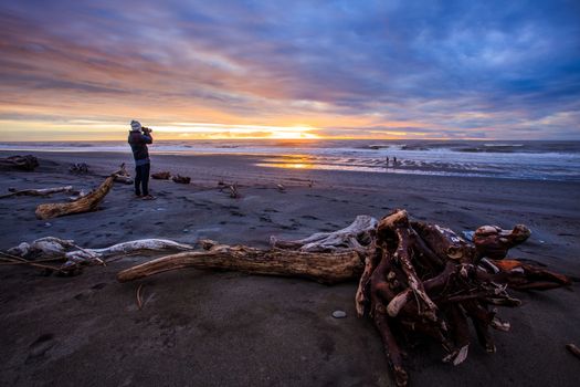 photographer and sun set on black beach hokitika south island new zealand 