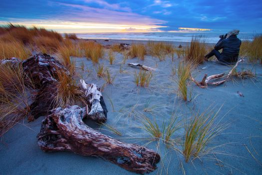 photographer on hokitika beach ,south island new zealand 