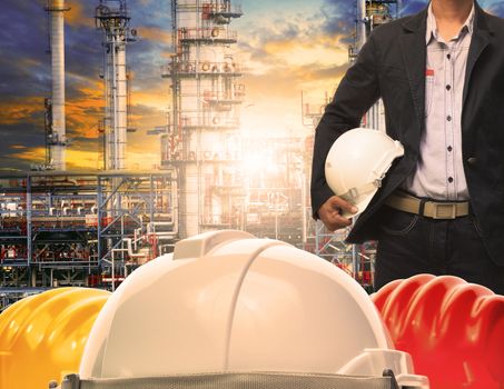 engineering man with white safety helmet standing in front of oil refinery building structure in heavy petrochemical industry 