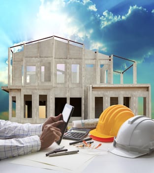 home construction and hand hold tablet on engineer working table use for real estate and construction business 