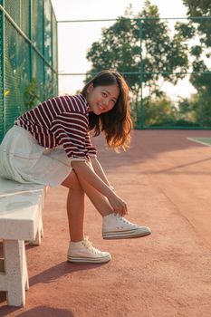 portrait of beautiful sport girl sitting in tennis courts looking to camera with smiling face use for people and healthy lifestyle activities