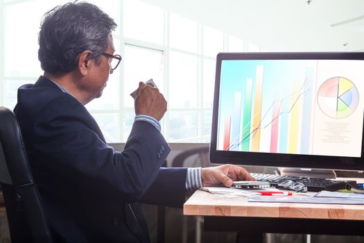 senior business man working on office table with computer and business graph report ,