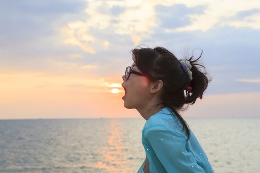 younger asian woman open mouth with sun set sky background