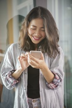 asian younger woman laughing with happiness emotion looking and message chat on smart phone 