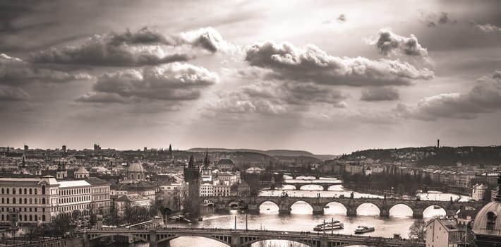 Monochrome image with the old center of Prague, the capital of Czech Republic, with its antique bridges and historical buildings, under a dramatic sky.