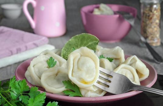Dumplings on a plate and a fork. Selective focus, gray wood background.
