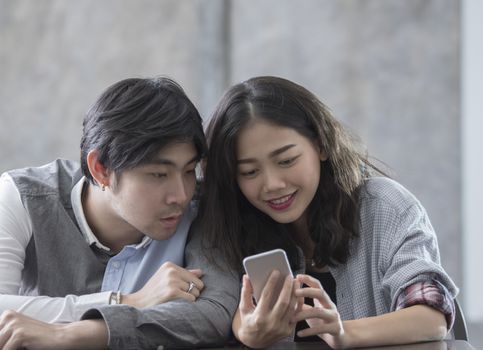 asian younger man and woman watching on smart phone with happy face,internet and social media concept