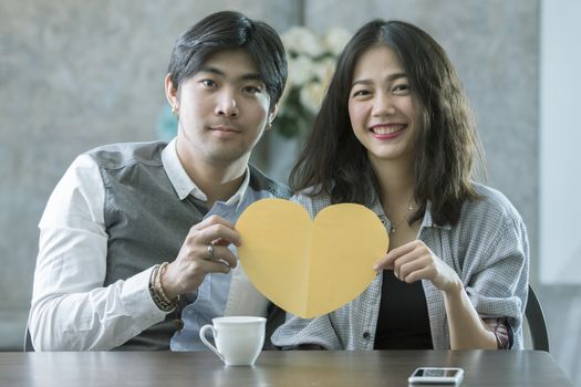 couples of asian man and woman holding heart shape paper cut with happiness emotion ,peple love conceptual