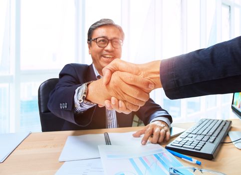 two business man shaking hand with happiness emotion after agreement in working solution ,shot on office working table