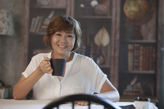 asian woman smiling face happiness emotion and coffee cup in hand sitting on wood table at home