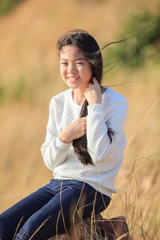 portrait of asian girl relaxing emotion sitting in grass field and windy evening use for teen age leisure and activities traveling vacation time